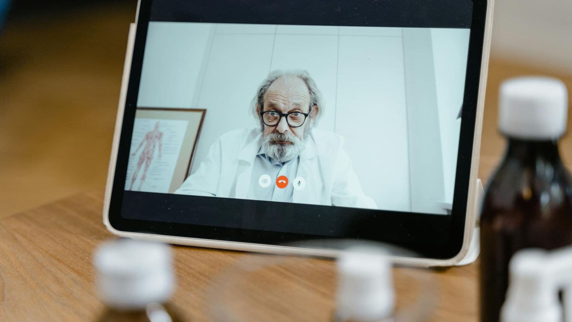 Elderly male doctor in white coat on a digital tablet screen during a virtual medical consultation.