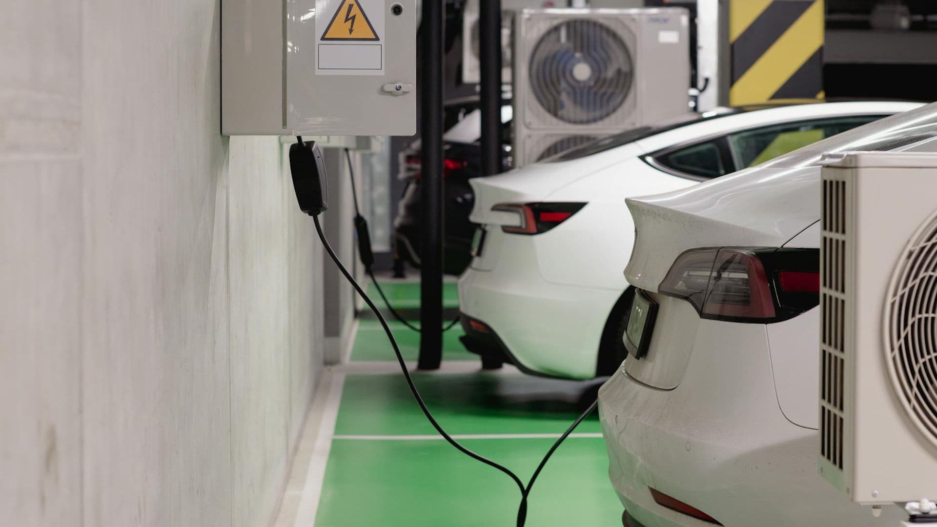 Electric vehicles charging at an indoor station in a modern underground garage.