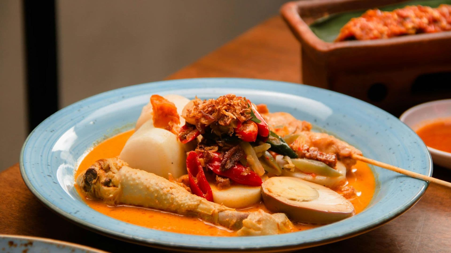 A vibrant and colorful traditional Indonesian dish featuring lontong sayur with chicken, vegetables, and eggs.