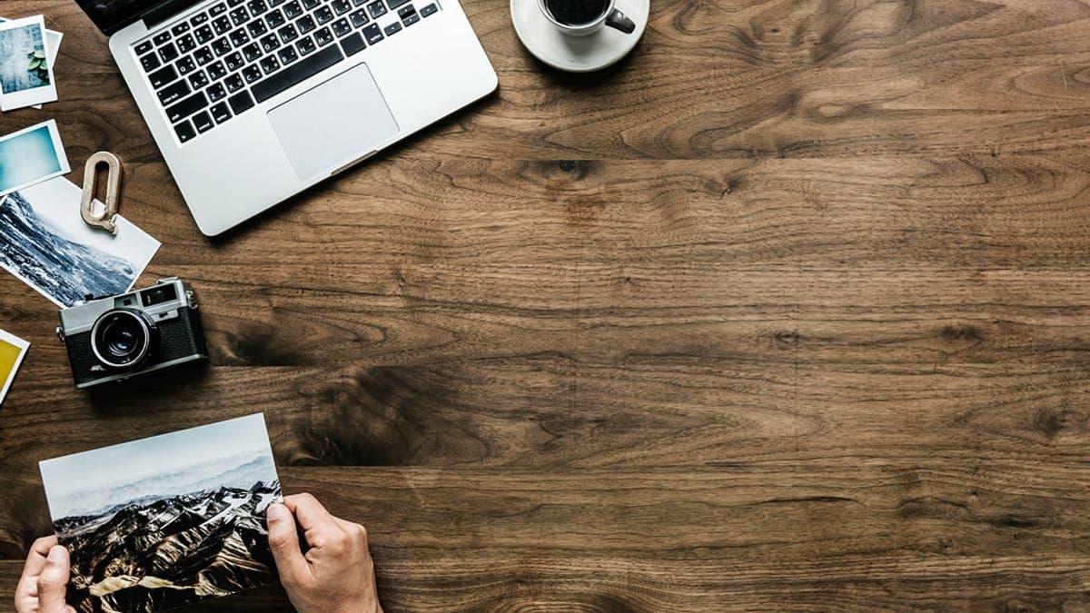 Meja kerja dengan laptop, kamera, dan foto: bahan media kit